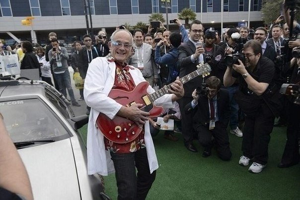 Christopher Lloyd en un DeLorean, con Google Glass y una guitarra Gibson en la exposición CES2014.