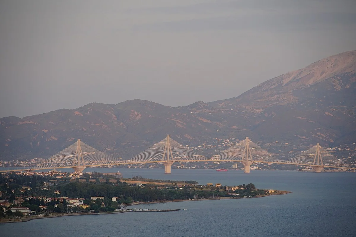 Мост Рио-Антирио с ночной белой подсветкой, отражающейся в водах залива